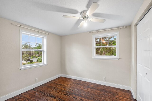 unfurnished bedroom featuring baseboards, dark wood finished floors, and a closet