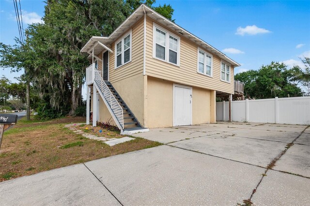exterior space with fence, stairs, and stucco siding