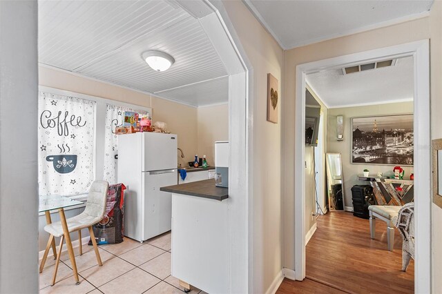 kitchen featuring visible vents, freestanding refrigerator, ornamental molding, dark countertops, and baseboards