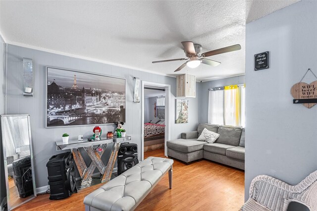 living room featuring ornamental molding, a textured ceiling, ceiling fan, and wood finished floors