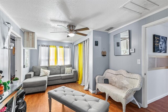 living area with visible vents, a textured ceiling, ceiling fan, and wood finished floors