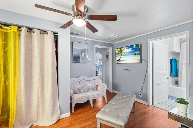 living area featuring baseboards, ornamental molding, light wood finished floors, and ceiling fan