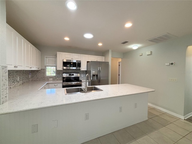 4480 Turnberry Ln, Lake Wales, FL 33859 - kitchen featuring backsplash, appliances with stainless steel finishes, a sink, white cabinets, and a peninsula