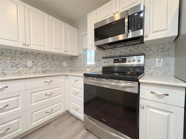 4480 Turnberry Ln, Lake Wales, FL 33859 - kitchen featuring backsplash, light countertops, white cabinets, stainless steel appliances, and light wood-style flooring