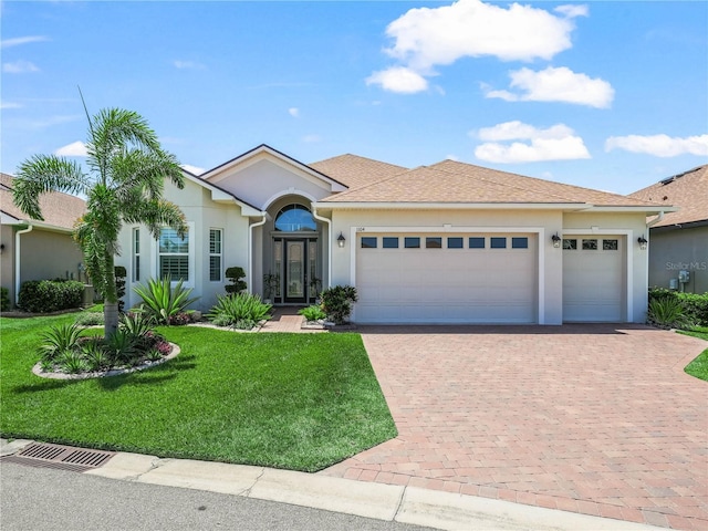 single story home featuring an attached garage, a front lawn, stucco siding, and decorative driveway