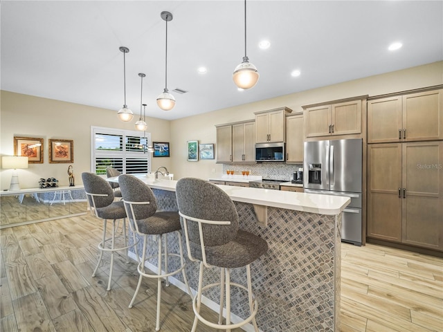 kitchen featuring visible vents, light wood-style flooring, appliances with stainless steel finishes, and a breakfast bar area