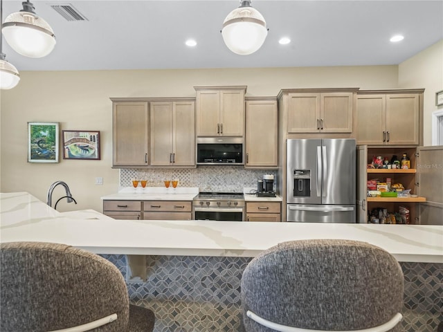 kitchen with appliances with stainless steel finishes, a sink, decorative light fixtures, backsplash, and visible vents