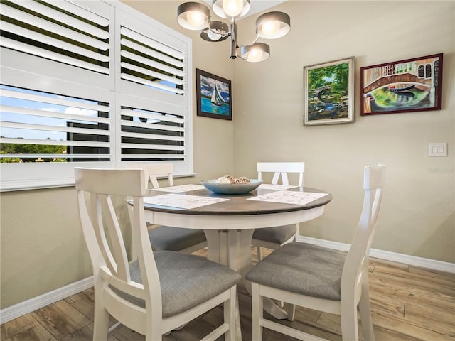 dining room with baseboards, a notable chandelier, and wood finished floors