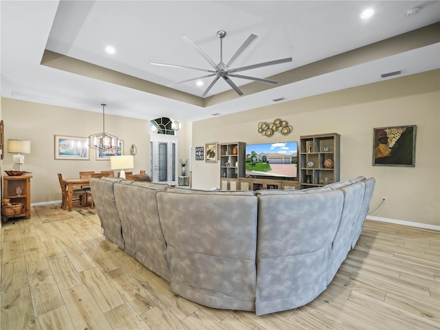 living room with a raised ceiling, recessed lighting, baseboards, light wood-type flooring, and visible vents