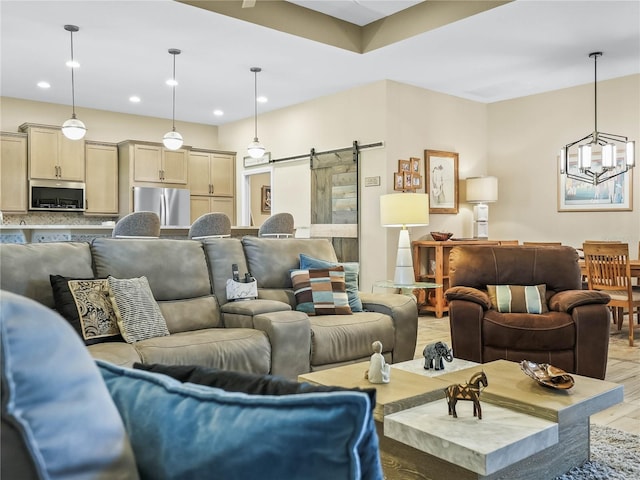 living area with light wood-style flooring, recessed lighting, a barn door, and a notable chandelier