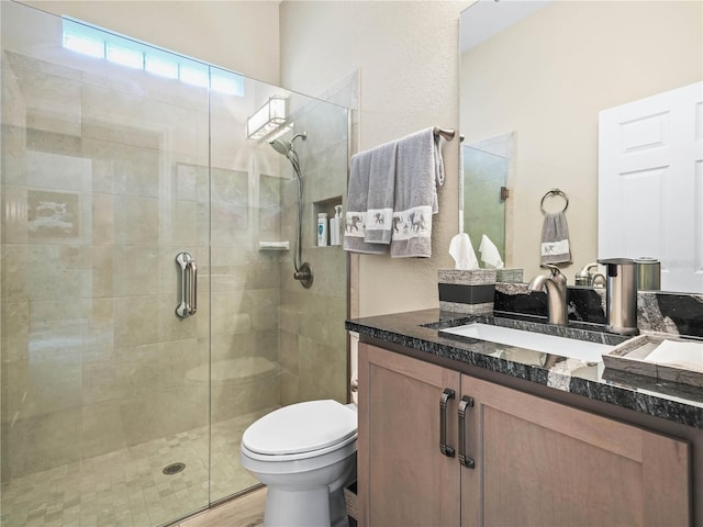 bathroom featuring toilet, a shower stall, wood finished floors, and vanity