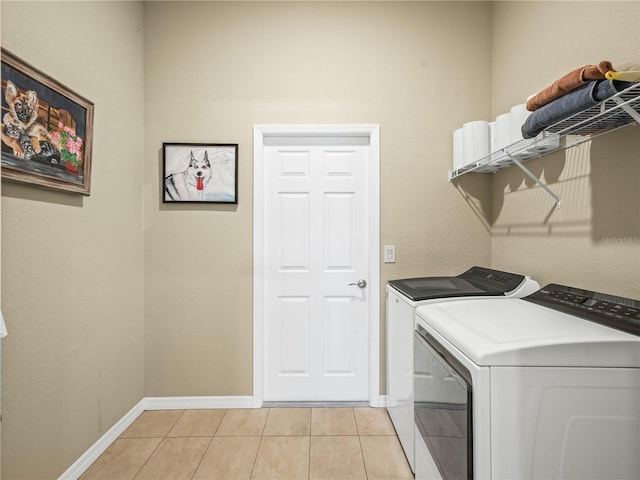 washroom featuring laundry area, baseboards, light tile patterned floors, and washing machine and dryer