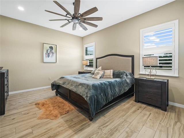 bedroom with a ceiling fan, baseboards, and light wood-style flooring