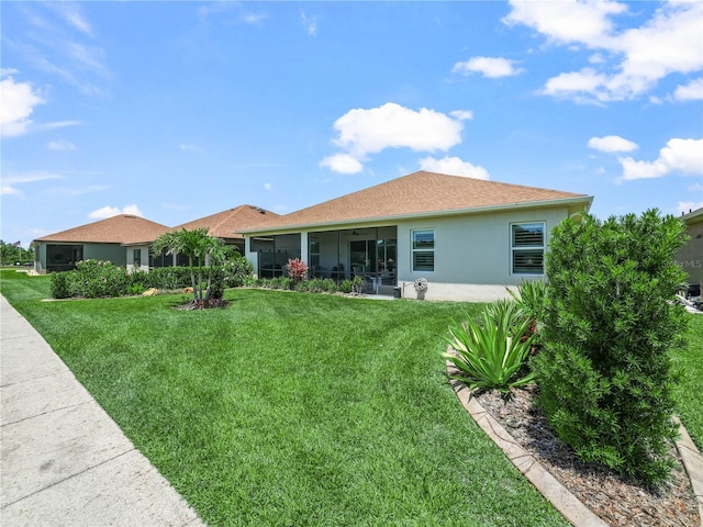 back of house featuring a yard, ceiling fan, a sunroom, and stucco siding