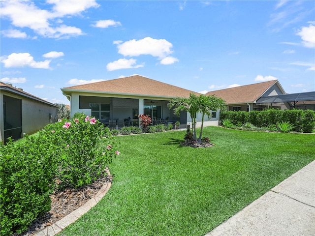 back of property with a lawn, a ceiling fan, and stucco siding