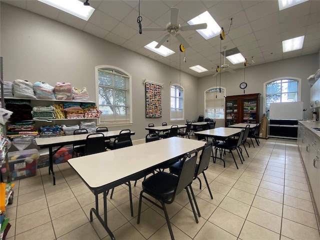 dining space with light tile patterned floors, a ceiling fan, and a paneled ceiling