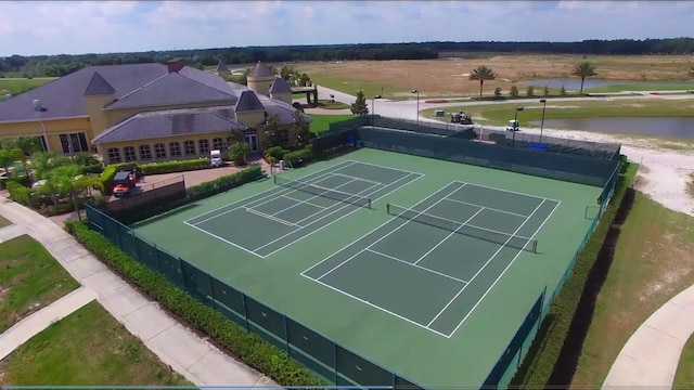 view of tennis court featuring a water view and fence