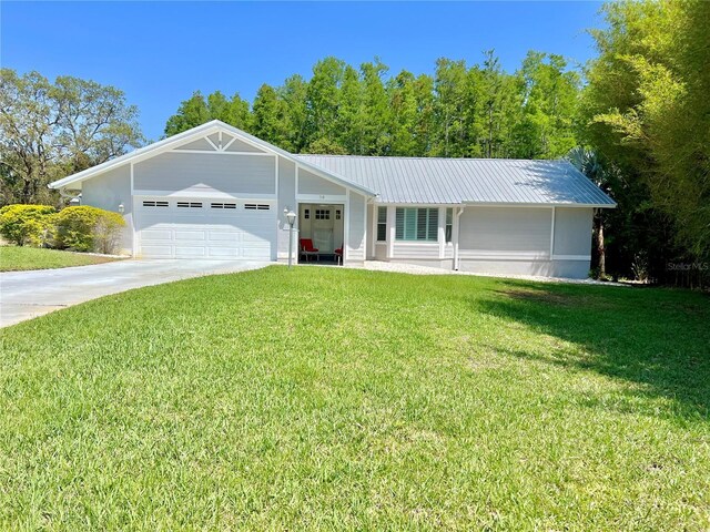 ranch-style house with an attached garage, concrete driveway, metal roof, and a front yard