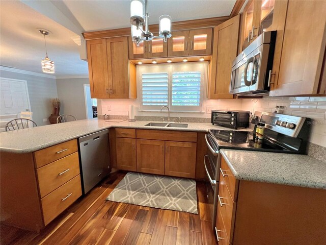 kitchen featuring brown cabinets, dark wood-style flooring, a sink, stainless steel appliances, and a peninsula