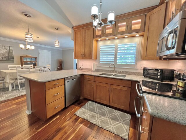 kitchen featuring crown molding, a peninsula, a sink, appliances with stainless steel finishes, and a notable chandelier