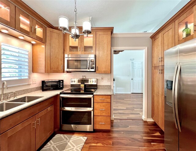 kitchen featuring dark wood-style flooring, brown cabinets, a sink, light countertops, and stainless steel appliances