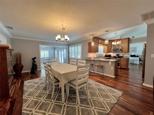 dining room featuring an inviting chandelier, a textured ceiling, dark wood-type flooring, visible vents, and ornamental molding