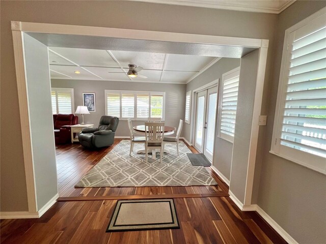 interior space with crown molding, baseboards, a ceiling fan, and dark wood-style floors