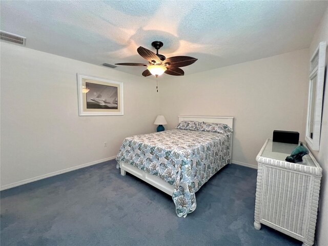 bedroom with visible vents, a textured ceiling, dark carpet, and ceiling fan