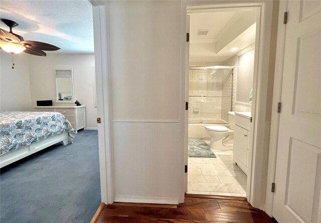 bedroom featuring connected bathroom, visible vents, ornamental molding, and a wainscoted wall
