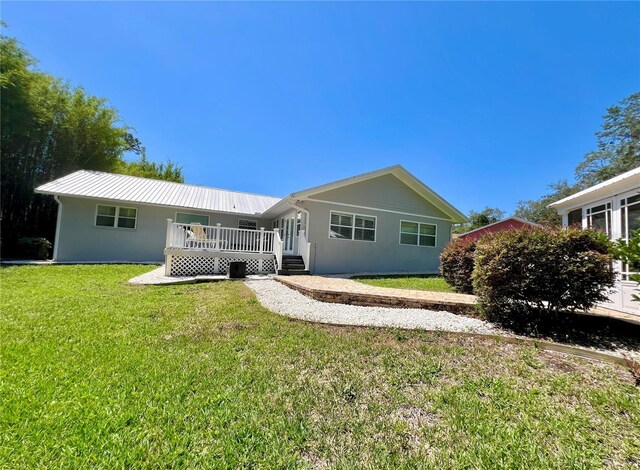view of front of property featuring stucco siding, metal roof, and a front yard
