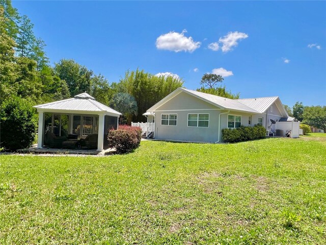 rear view of property with a lawn, a gazebo, and metal roof