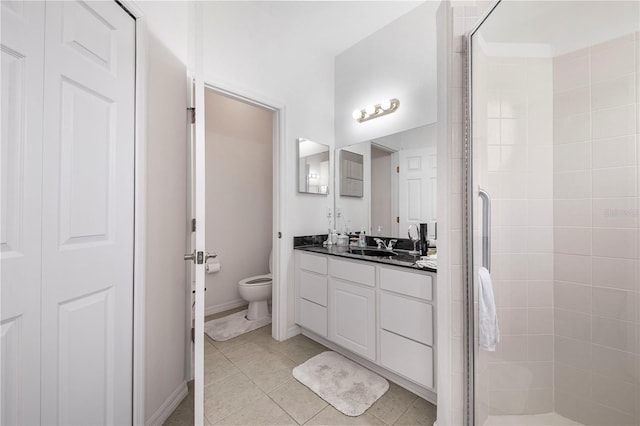 full bath with a shower stall, toilet, vanity, and tile patterned floors