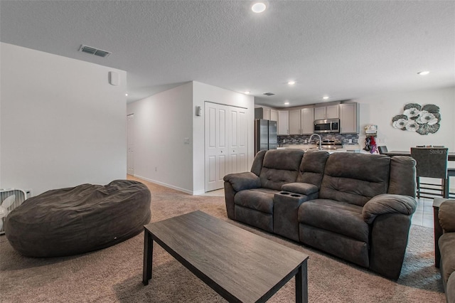 living area featuring recessed lighting, a textured ceiling, visible vents, and light carpet
