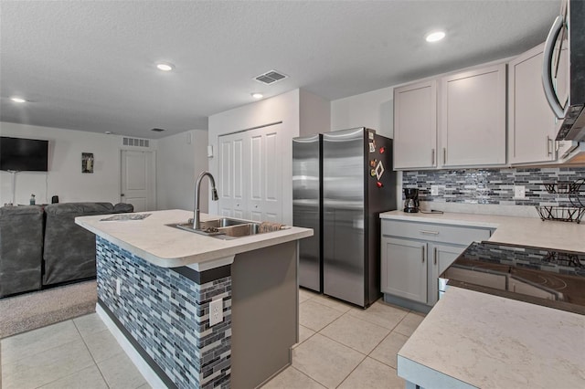 kitchen featuring appliances with stainless steel finishes, a sink, light countertops, open floor plan, and visible vents