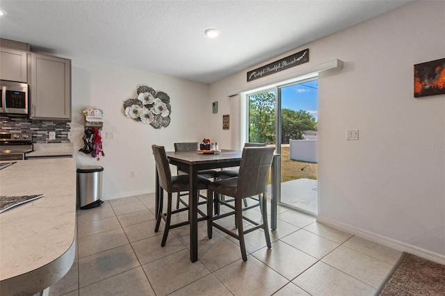 dining space featuring recessed lighting, baseboards, light tile patterned floors, and a textured ceiling