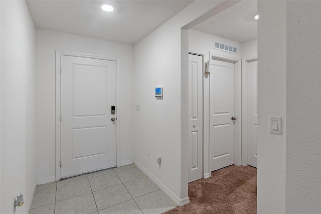 foyer entrance with baseboards, visible vents, and light tile patterned floors