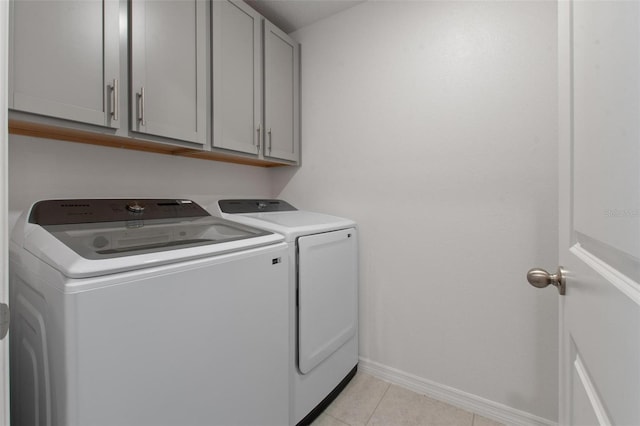 laundry room featuring baseboards, washer and clothes dryer, cabinet space, and light tile patterned floors
