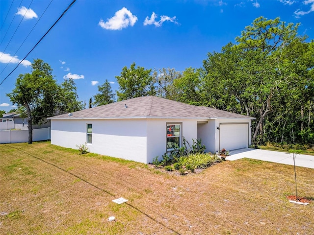 view of side of home featuring driveway, a lawn, a garage, fence, and stucco siding