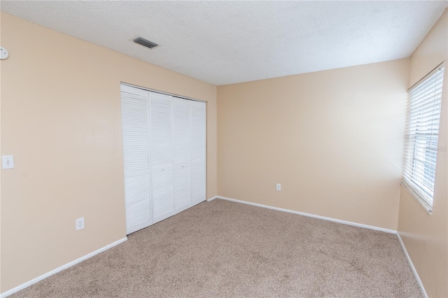 unfurnished bedroom with visible vents, baseboards, carpet floors, and a closet