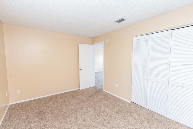 unfurnished bedroom with carpet flooring, baseboards, visible vents, and a closet