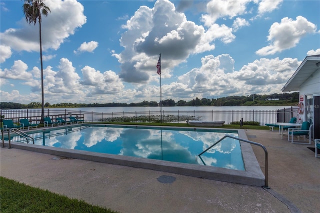 community pool with a patio, a water view, and fence