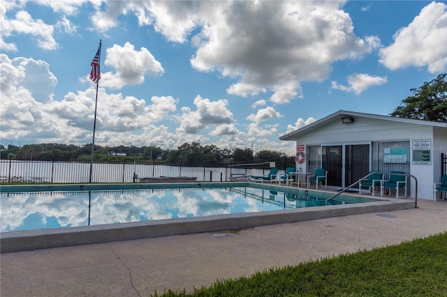 community pool with a water view, a patio area, and fence