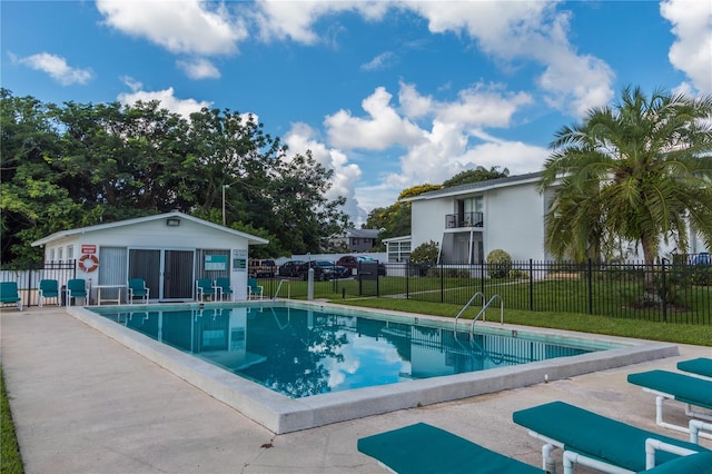 community pool featuring a lawn, fence, an outdoor structure, and a patio area