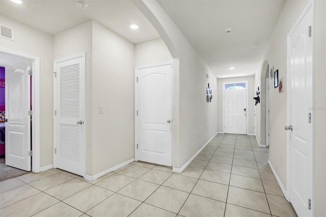 hall featuring arched walkways, recessed lighting, and light tile patterned flooring