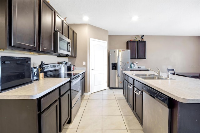 kitchen with light tile patterned flooring, dark brown cabinets, a sink, light countertops, and stainless steel appliances