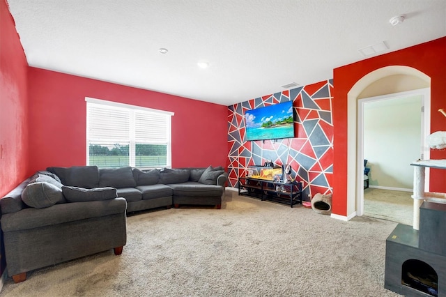 carpeted living room featuring arched walkways, baseboards, an accent wall, and visible vents