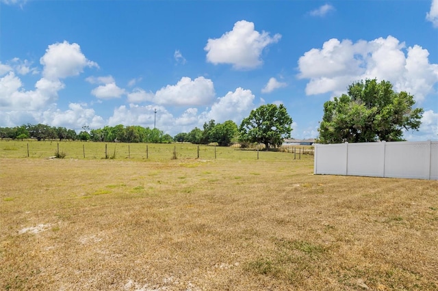 view of yard with fence and a rural view