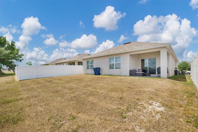 back of house featuring a lawn, stucco siding, an outdoor hangout area, and fence