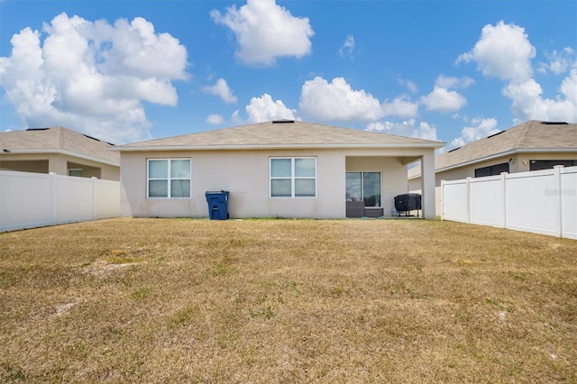 back of property with a fenced backyard, stucco siding, and a yard