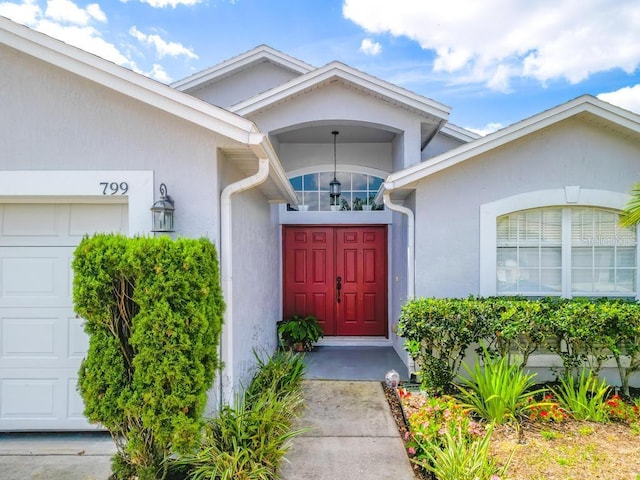 property entrance featuring an attached garage and stucco siding